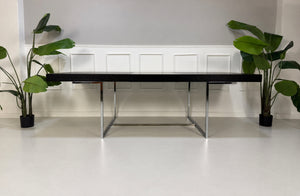 Gebrauchter grauer B&B Italia Athos Designer Chrom Tisch vor einer Wand, stilvoll und modern eingerichtet.