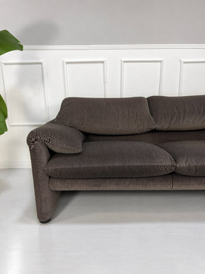 Gebrauchtes braun-schwarzes Cassina Maralunga Designer Stoff Sofa vor einer Wand, stilvoll und modern eingerichtet.