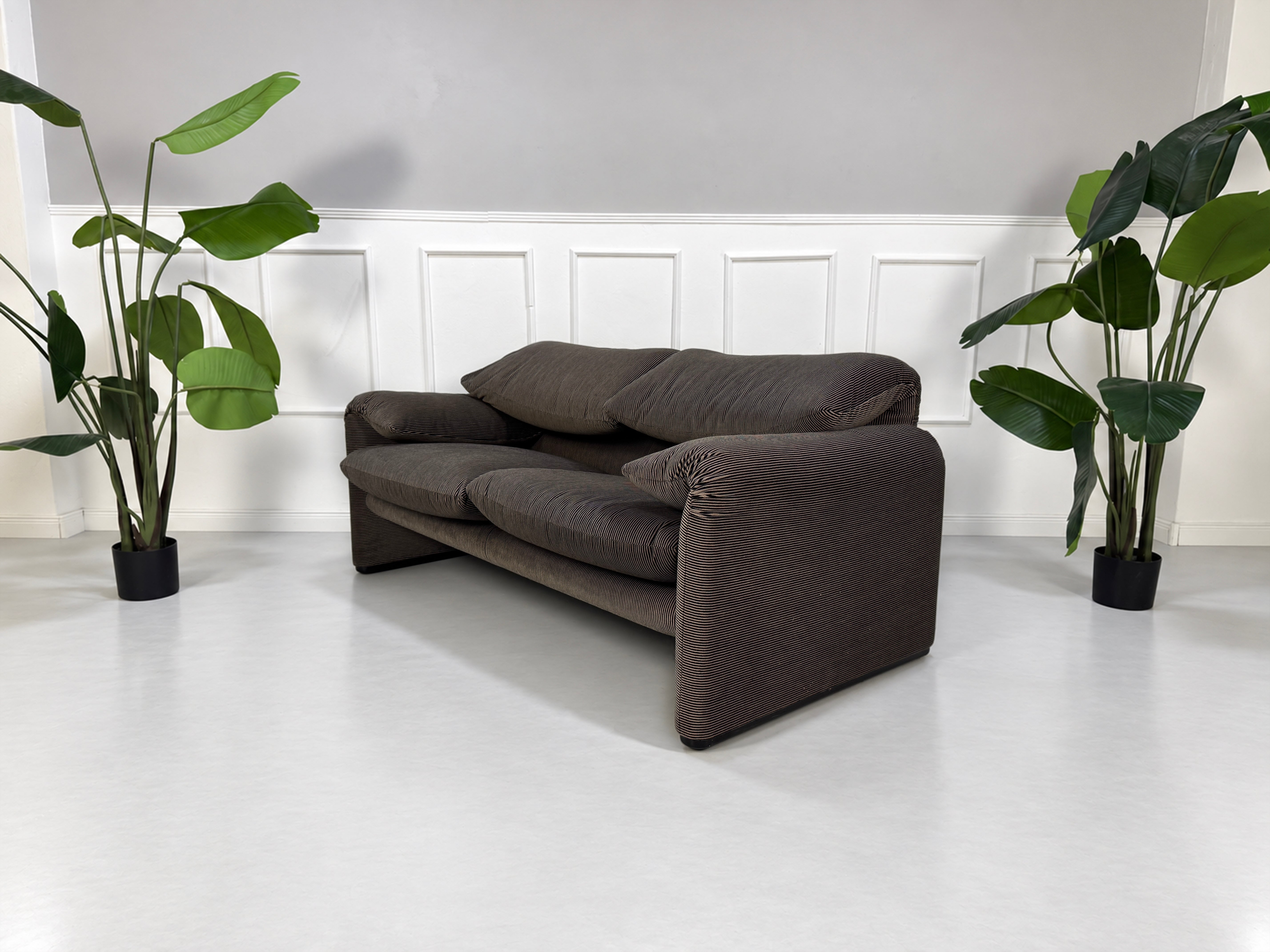 Gebrauchtes braun-schwarzes Cassina Maralunga Designer Stoff Sofa vor einer Wand, stilvoll und modern eingerichtet.