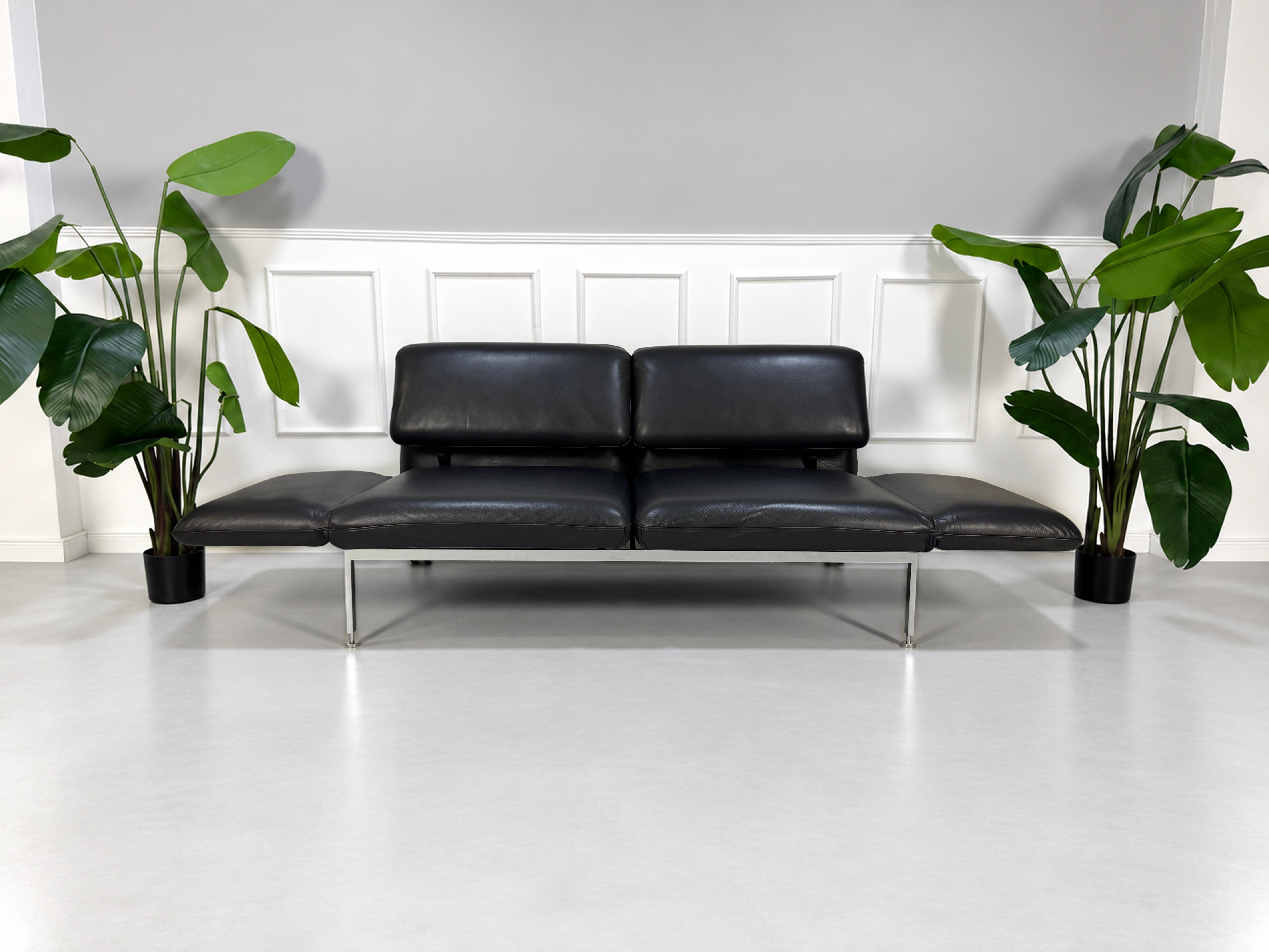 Gebrauchtes graues Brühl Roro Medium Designer Leder Sofa vor einer Wand, stilvoll und modern eingerichtet.