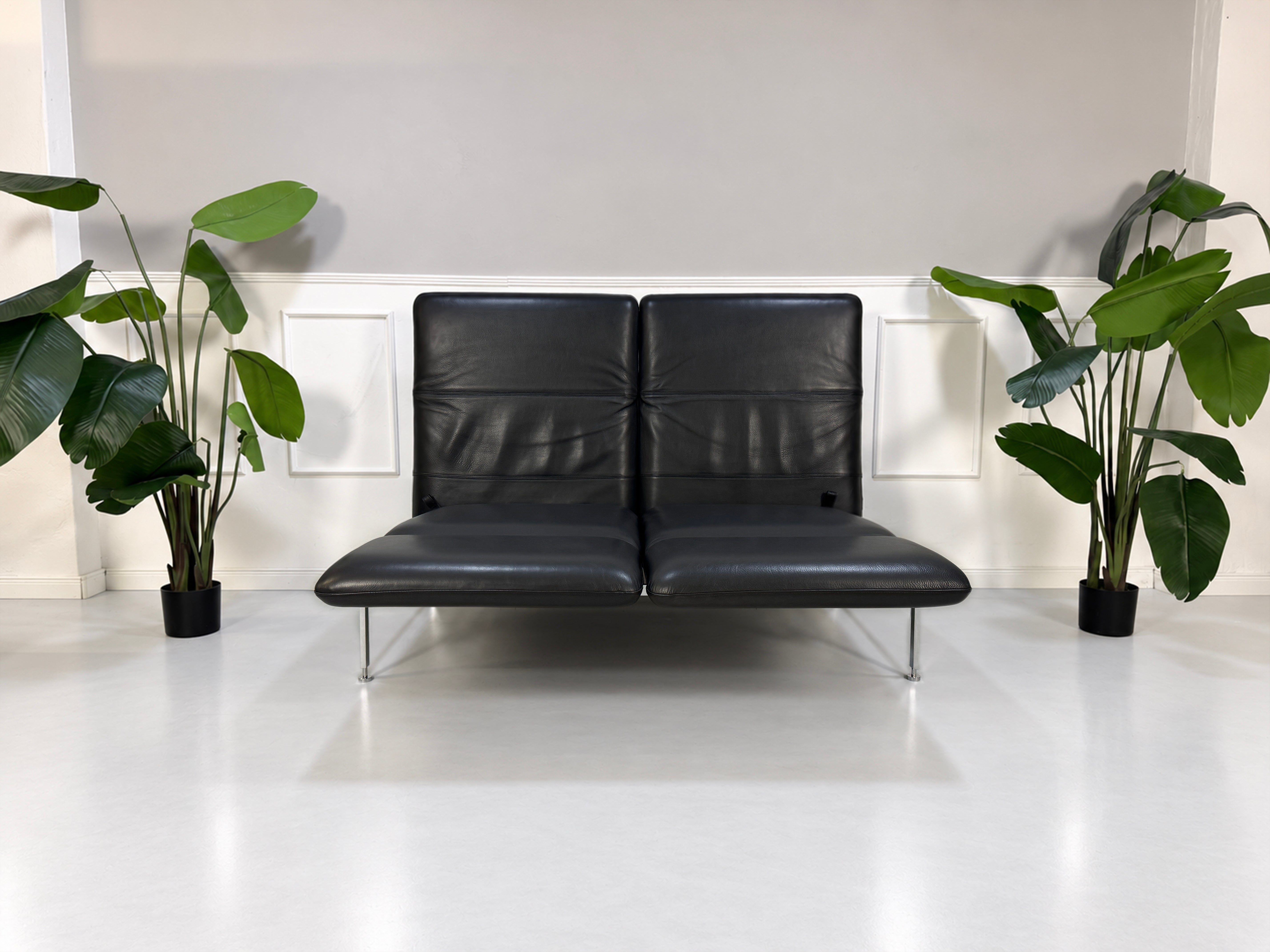 Gebrauchtes graues Brühl Roro Medium Designer Leder Sofa vor einer Wand, stilvoll und modern eingerichtet.