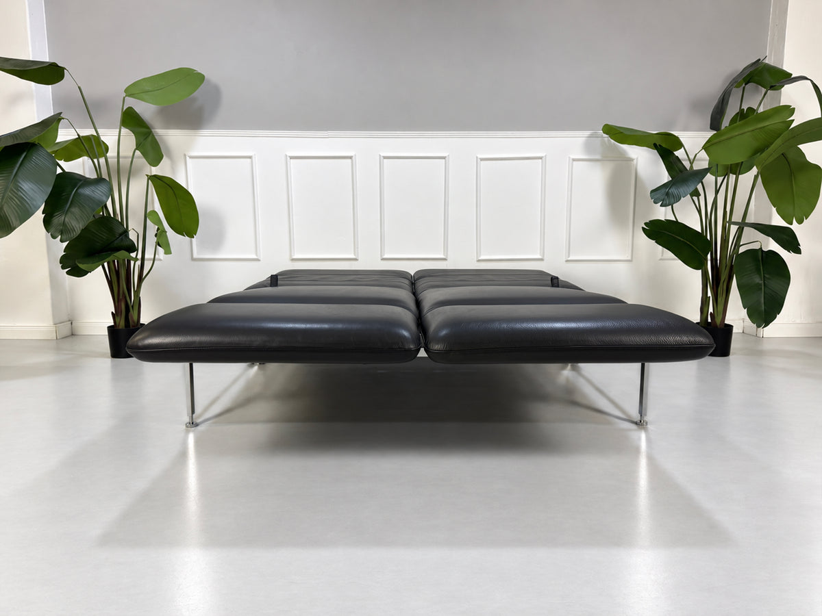 Gebrauchtes graues Brühl Roro Medium Designer Leder Sofa vor einer Wand, stilvoll und modern eingerichtet.