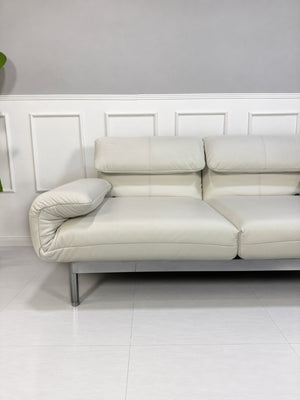 Gebrauchtes weißes Rolf Benz Plura 380 Designer Leder Sofa vor einer Wand, stilvoll und modern eingerichtet.