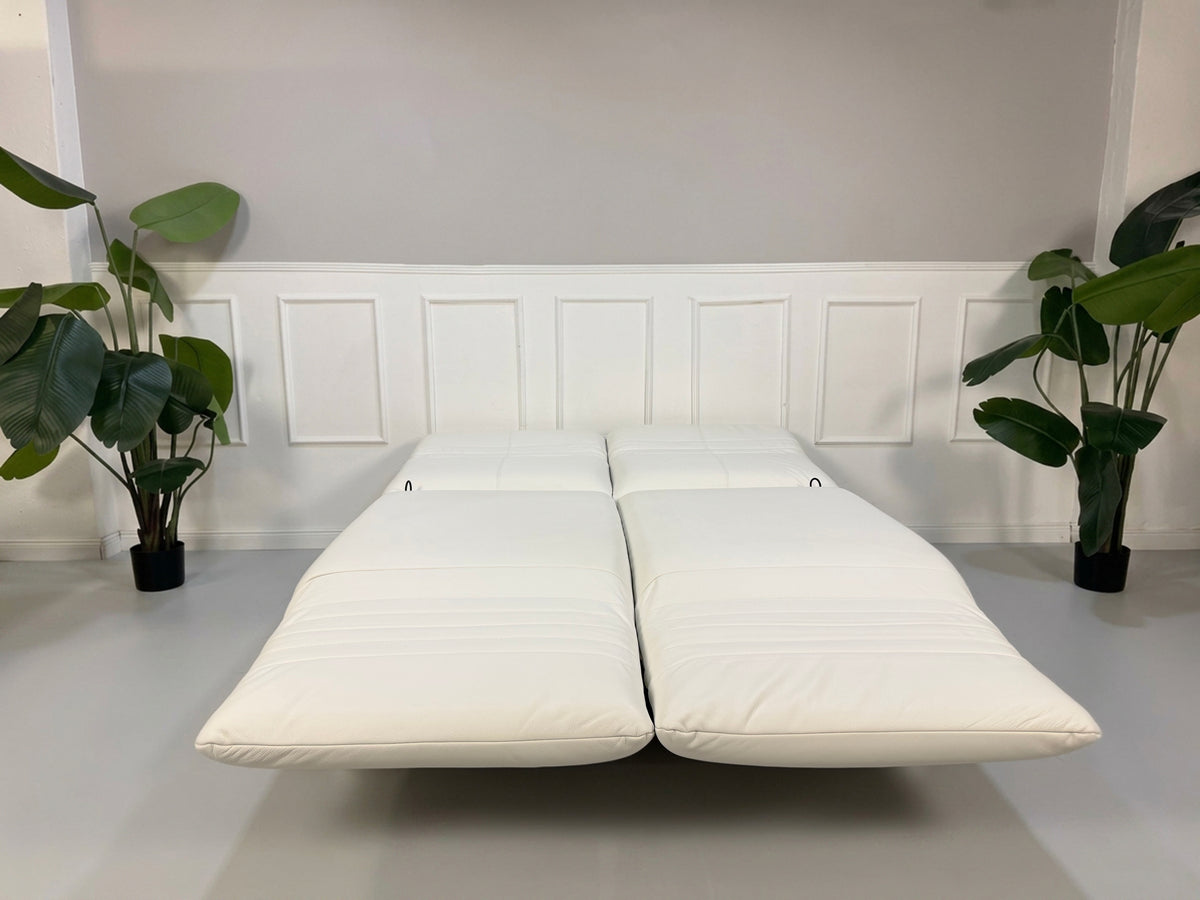 Gebrauchtes weißes Rolf Benz Plura 380 Designer Leder Sofa vor einer Wand, stilvoll und modern eingerichtet.