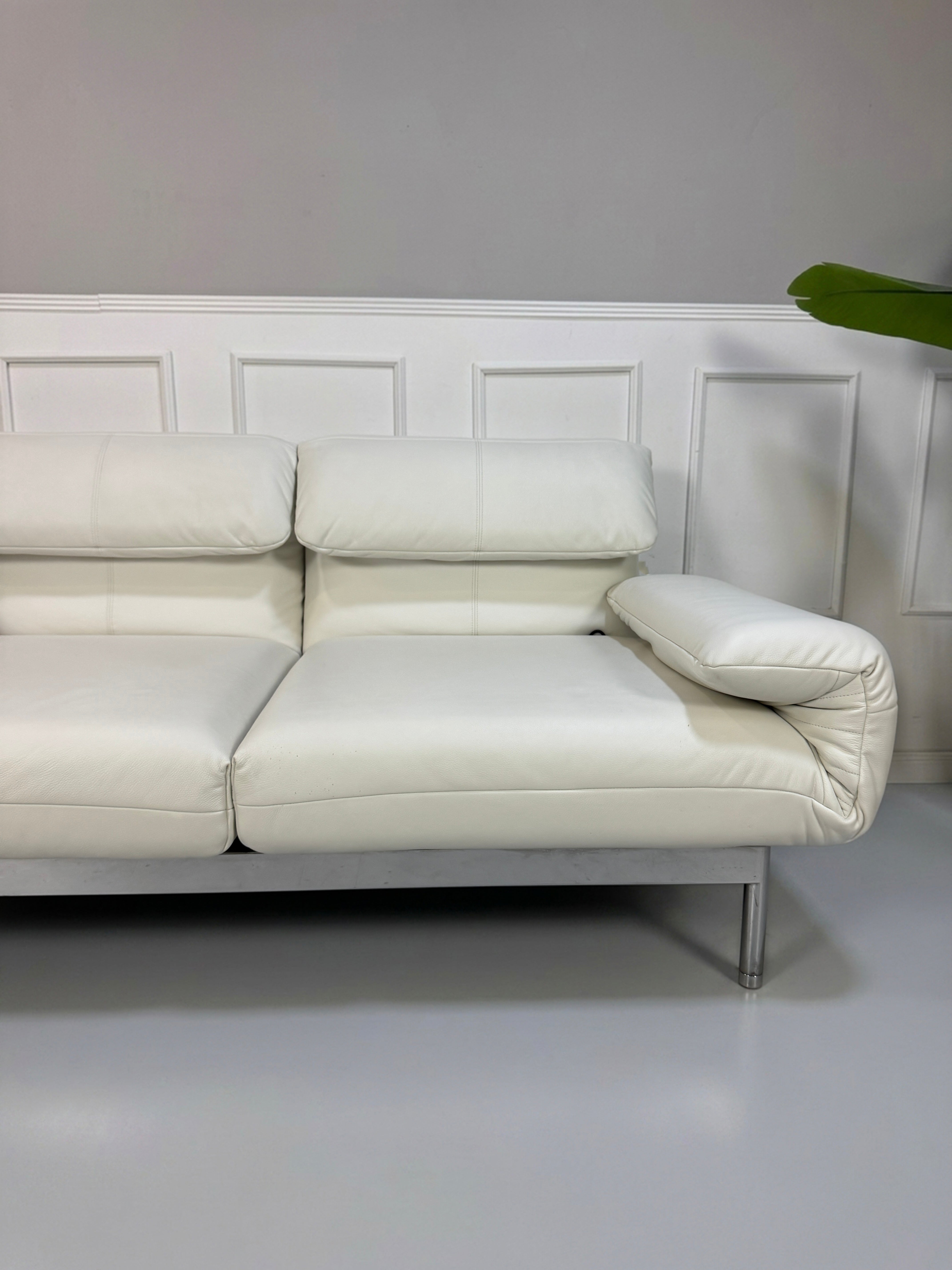 Gebrauchtes weißes Rolf Benz Plura 380 Designer Leder Sofa vor einer Wand, stilvoll und modern eingerichtet.