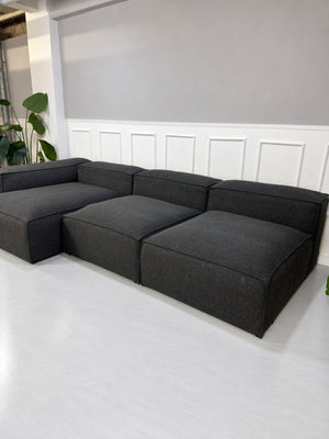 Gebrauchtes graues Bolia Cosima Designer Stoff Sofa vor einer Wand, stilvoll und modern eingerichtet.
