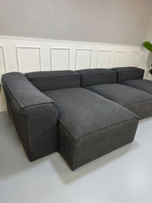 Gebrauchtes graues Bolia Cosima Designer Stoff Sofa vor einer Wand, stilvoll und modern eingerichtet.