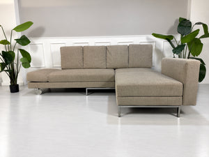 Gebrauchtes grau-beiges Brühl Fourtwo Designer Stoff Ecksofa vor einer Wand, stilvoll und modern eingerichtet.