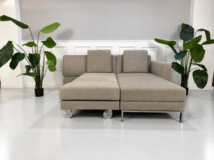 Gebrauchtes grau-beiges Brühl Fourtwo Designer Stoff Ecksofa vor einer Wand, stilvoll und modern eingerichtet.