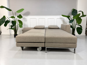 Gebrauchtes grau-beiges Brühl Fourtwo Designer Stoff Ecksofa vor einer Wand, stilvoll und modern eingerichtet.
