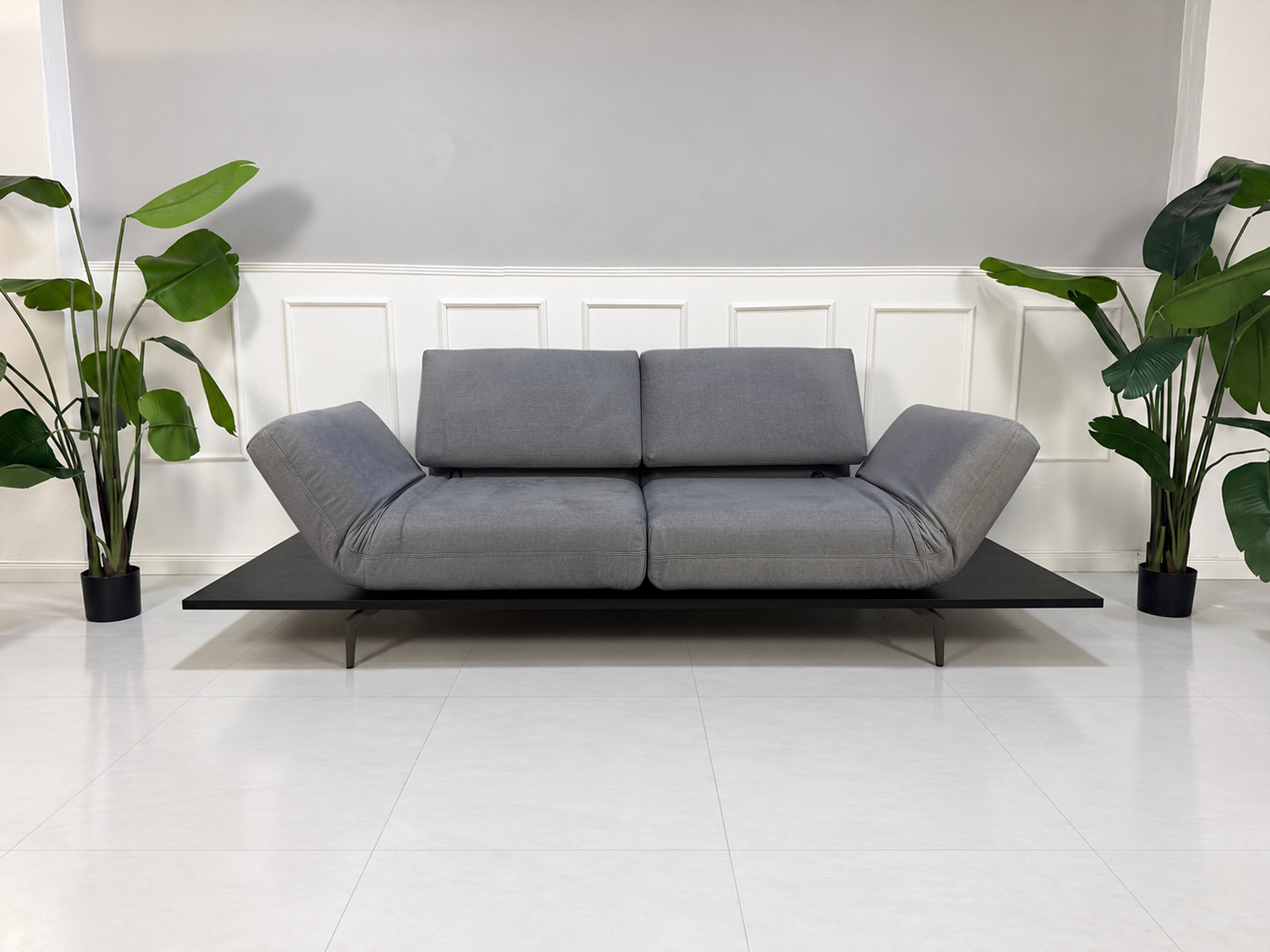 Gebrauchtes grau-blaues Rolf Benz Aura Designer Stoff Sofa vor einer Wand, stilvoll und modern eingerichtet.
