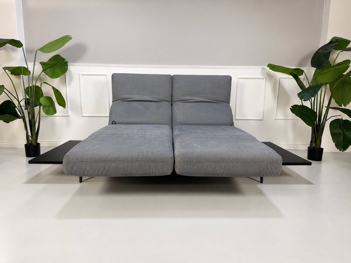 Gebrauchtes grau-blaues Rolf Benz Aura Designer Stoff Sofa vor einer Wand, stilvoll und modern eingerichtet.