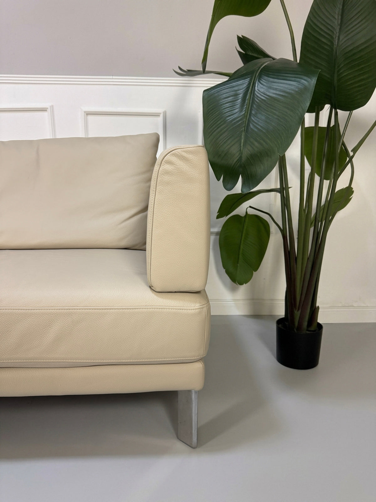 Gebrauchtes beiges Rolf Benz Sento 344 Designer Leder Ecksofa mit Hockerbank vor einer Wand, stilvoll und modern eingerichtet.