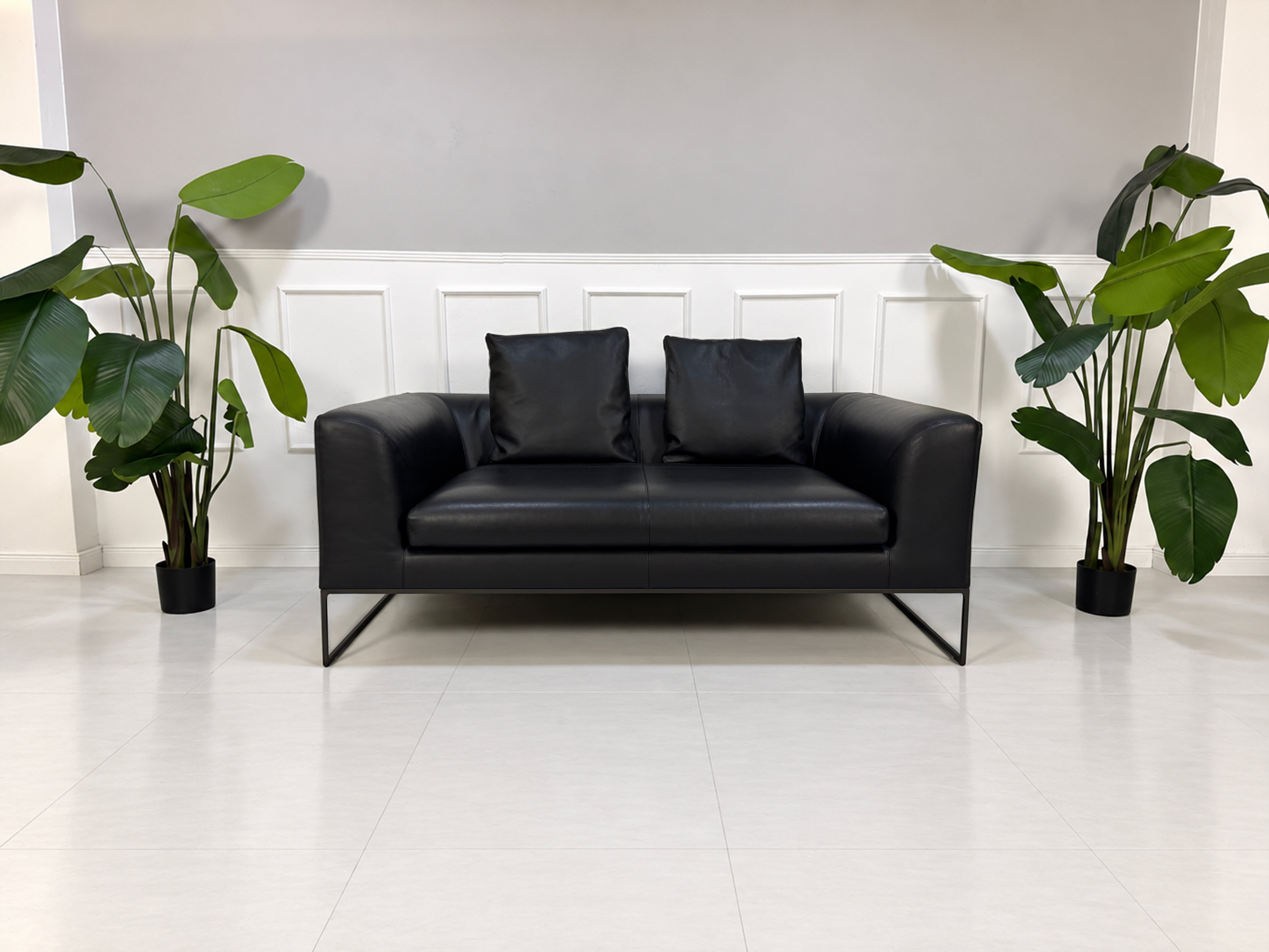 Gebrauchtes schwarzes COR Mell Designer Leder Sofa vor einer Wand, stilvoll und modern eingerichtet.