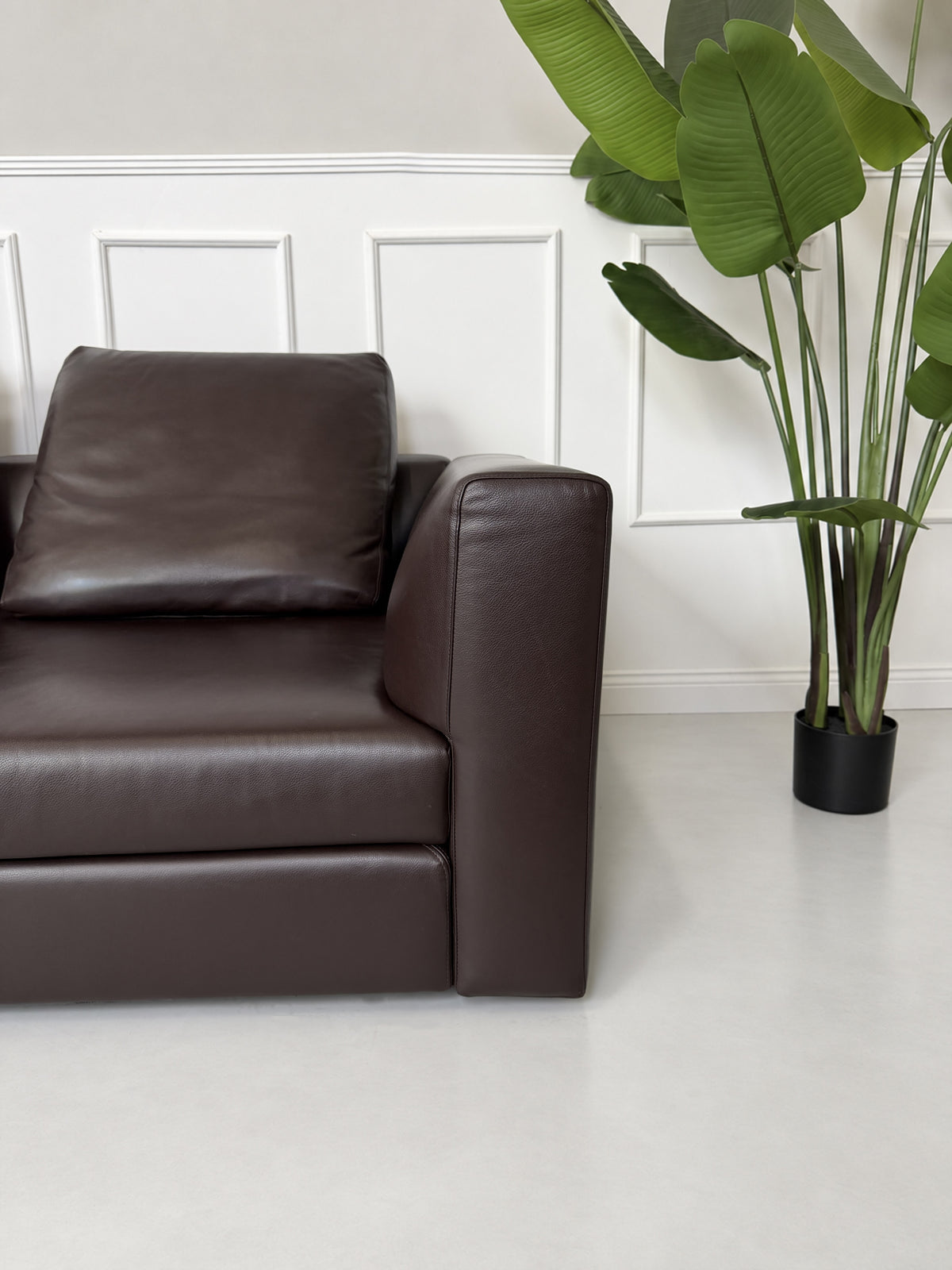Gebrauchtes braunes Minotti Kline Designer Leder Ecksofa mit Hocker vor einer Wand, stilvoll und modern eingerichtet.