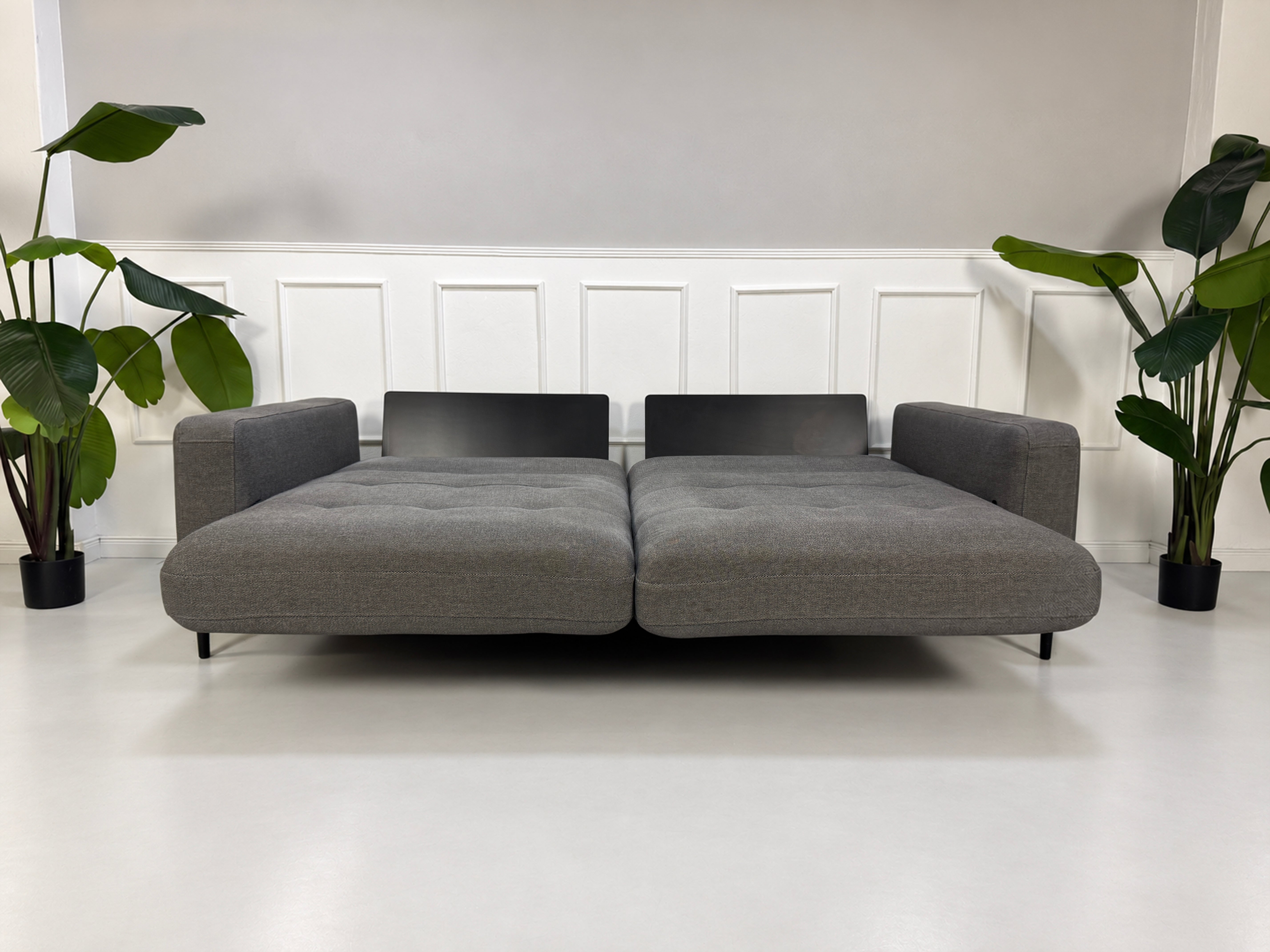 Gebrauchtes graues Rolf Benz Tira Designer Stoff Sofa vor einer Wand, stilvoll und modern eingerichtet.