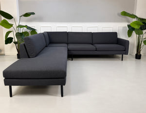 Gebrauchtes blaues Bolia Scandinavia Remix Designer Stoff Ecksofa vor einer Wand, stilvoll und modern eingerichtet.