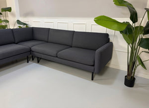 Gebrauchtes blaues Bolia Scandinavia Remix Designer Stoff Ecksofa vor einer Wand, stilvoll und modern eingerichtet.