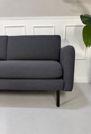 Gebrauchtes blaues Bolia Scandinavia Remix Designer Stoff Ecksofa vor einer Wand, stilvoll und modern eingerichtet.