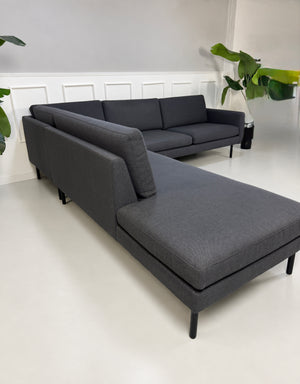 Gebrauchtes blaues Bolia Scandinavia Remix Designer Stoff Ecksofa vor einer Wand, stilvoll und modern eingerichtet.