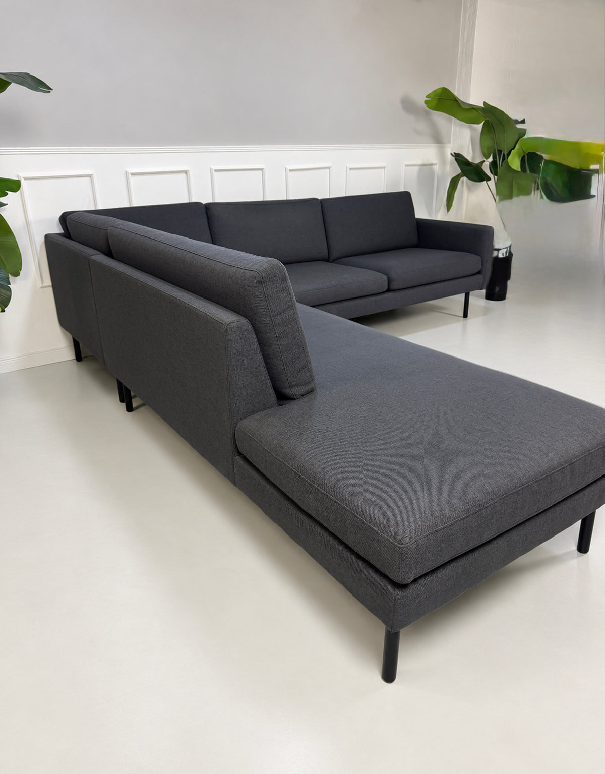 Gebrauchtes blaues Bolia Scandinavia Remix Designer Stoff Ecksofa vor einer Wand, stilvoll und modern eingerichtet.