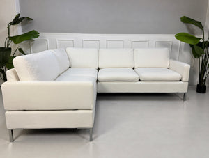 Gebrauchtes weißes Brühl Alba Designer Stoff Ecksofa vor einer Wand, stilvoll und modern eingerichtet.