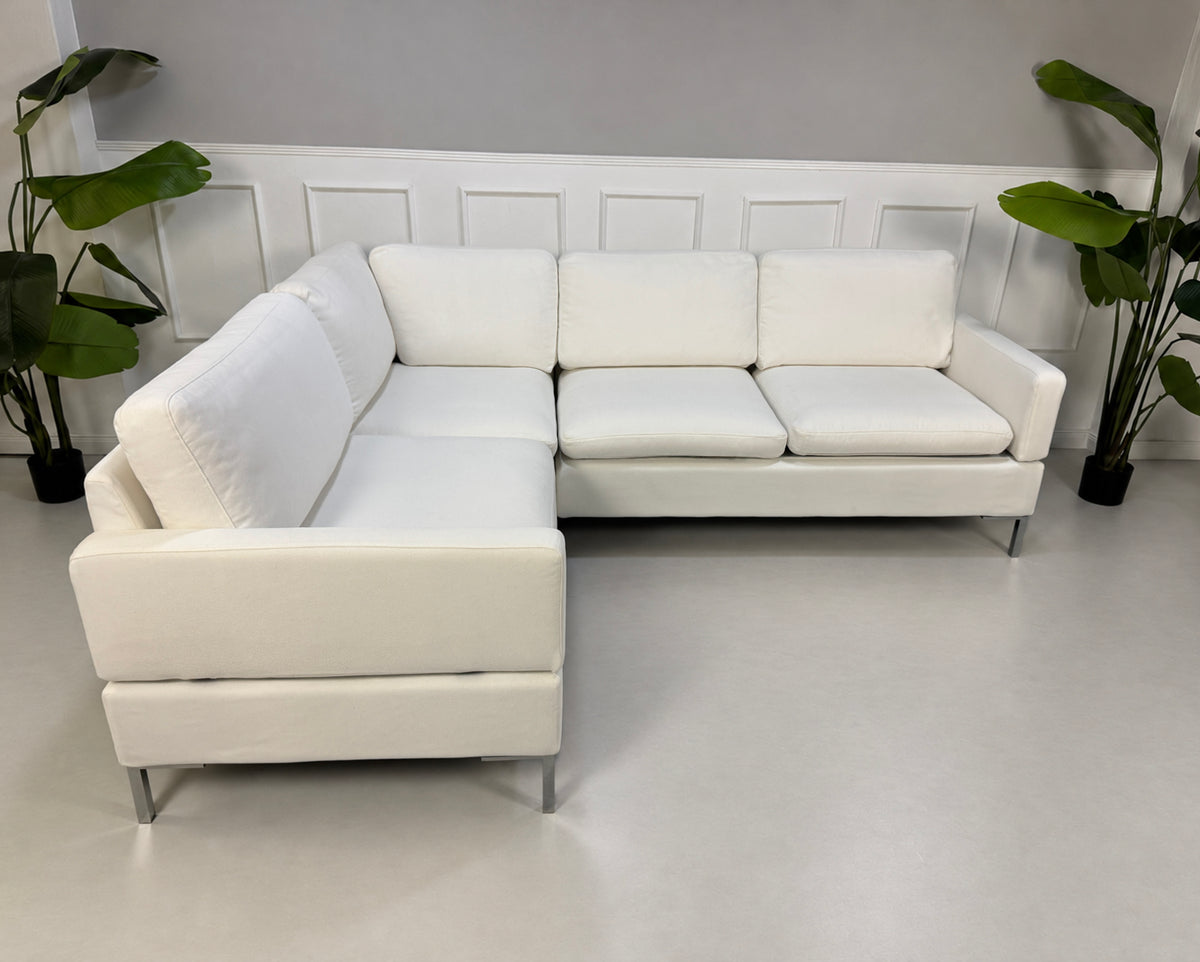Gebrauchtes weißes Brühl Alba Designer Stoff Ecksofa vor einer Wand, stilvoll und modern eingerichtet.