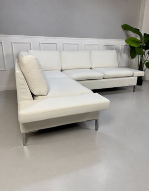 Gebrauchtes weißes Brühl Alba Designer Stoff Ecksofa vor einer Wand, stilvoll und modern eingerichtet.
