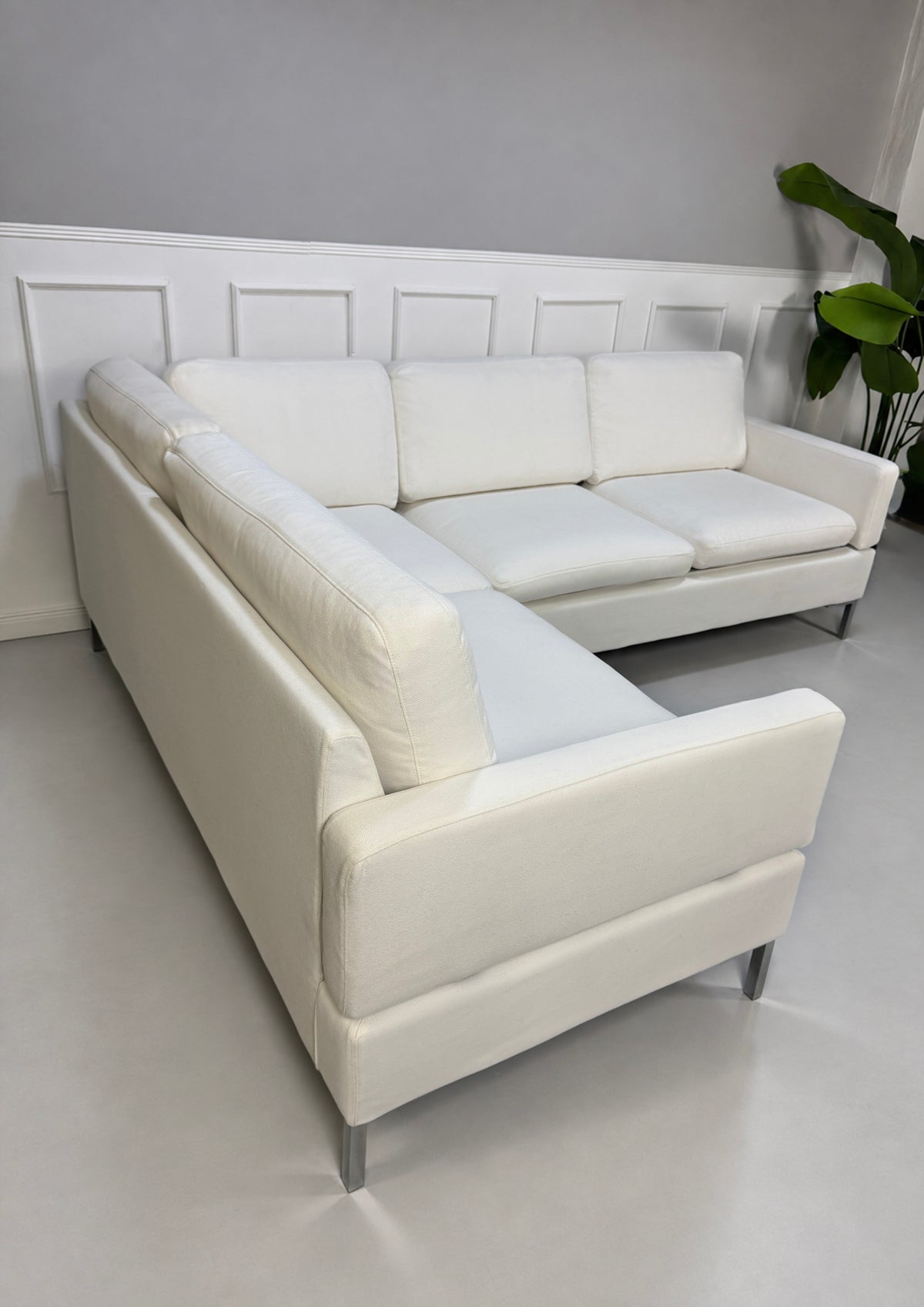 Gebrauchtes weißes Brühl Alba Designer Stoff Ecksofa vor einer Wand, stilvoll und modern eingerichtet.