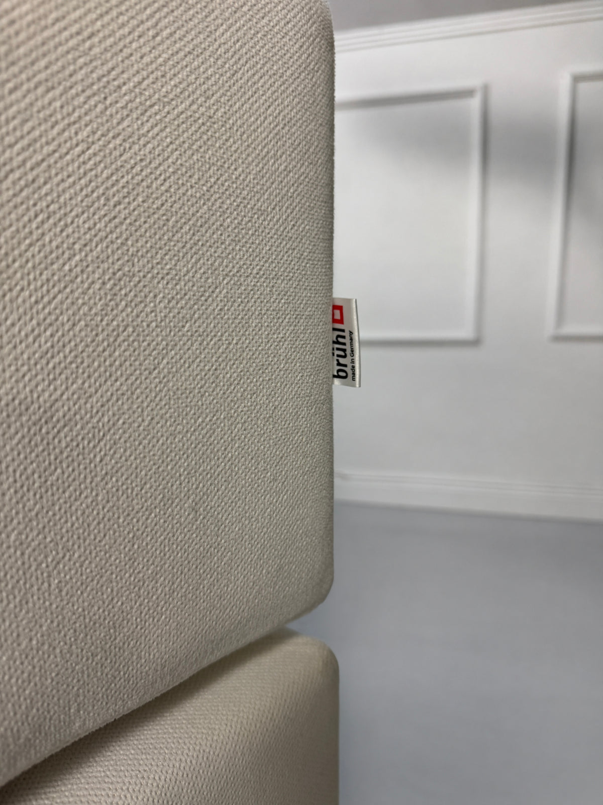 Gebrauchtes weißes Brühl Alba Designer Stoff Ecksofa vor einer Wand, stilvoll und modern eingerichtet.
