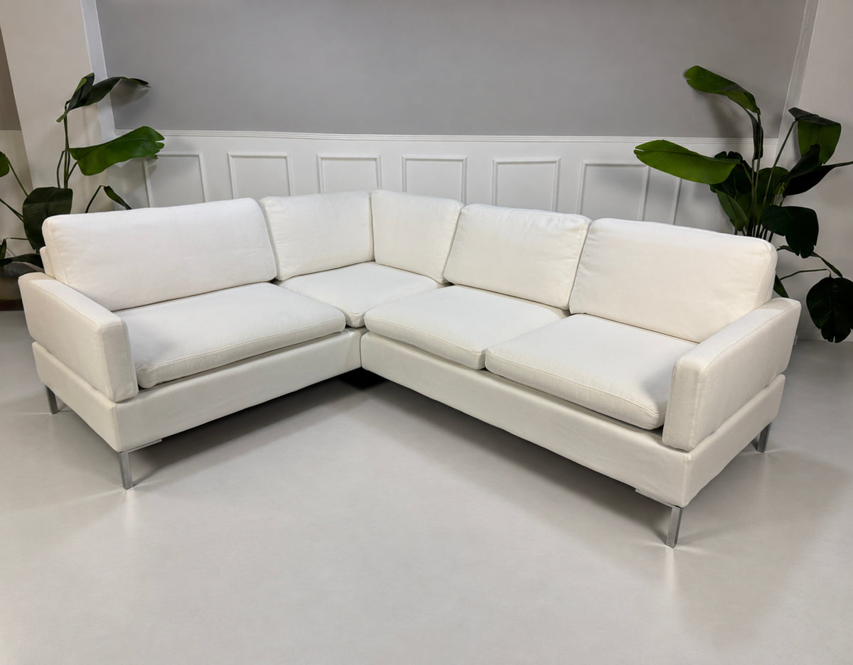 Gebrauchtes weißes Brühl Alba Designer Stoff Ecksofa vor einer Wand, stilvoll und modern eingerichtet.