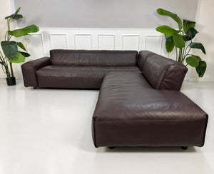 Gebrauchtes braunes Rolf Benz Mio Designer Leder Ecksofa vor einer Wand, stilvoll und modern eingerichtet.