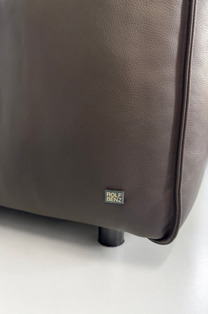 Gebrauchtes braunes Rolf Benz Mio Designer Leder Ecksofa vor einer Wand, stilvoll und modern eingerichtet.