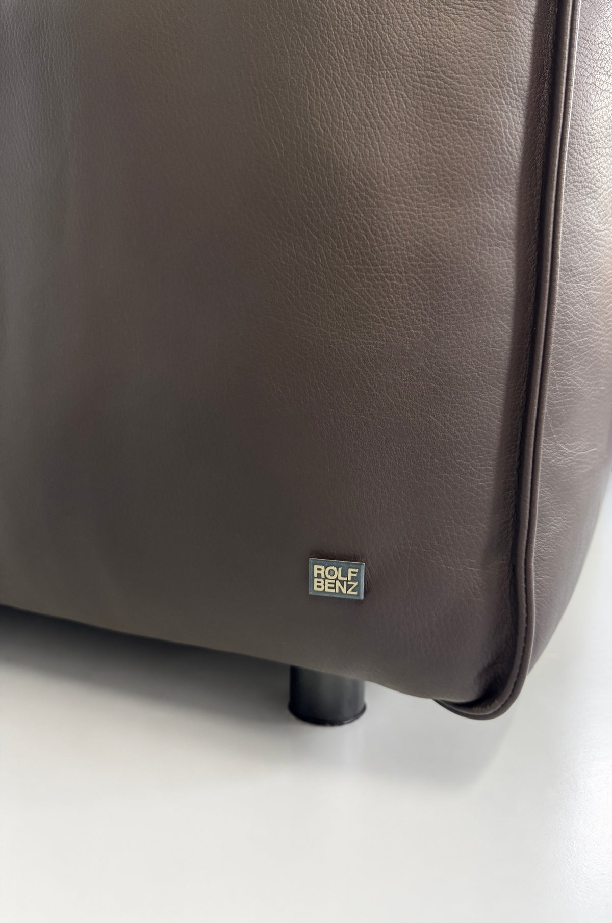 Gebrauchtes braunes Rolf Benz Mio Designer Leder Ecksofa vor einer Wand, stilvoll und modern eingerichtet.