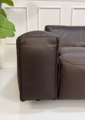 Gebrauchtes braunes Rolf Benz Mio Designer Leder Ecksofa vor einer Wand, stilvoll und modern eingerichtet.
