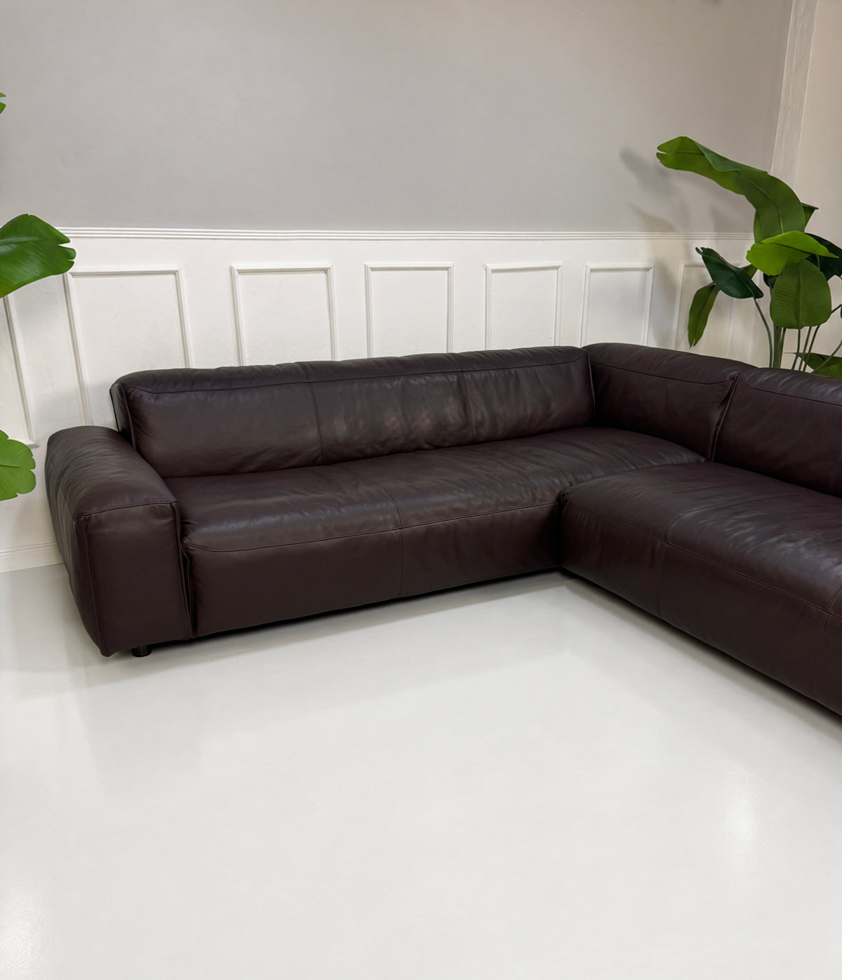Gebrauchtes braunes Rolf Benz Mio Designer Leder Ecksofa vor einer Wand, stilvoll und modern eingerichtet.