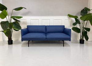 Gebrauchtes blaues Muuto Outline Designer Leder Sofa vor einer Wand, stilvoll und modern eingerichtet.