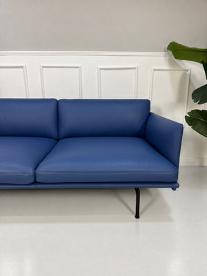 Gebrauchtes blaues Muuto Outline Designer Leder Sofa vor einer Wand, stilvoll und modern eingerichtet.