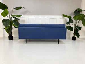 Gebrauchtes blaues Muuto Outline Designer Leder Sofa vor einer Wand, stilvoll und modern eingerichtet.