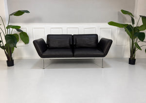 Gebrauchtes schwarzes Brühl Roro Medium Designer Leder Sofa vor einer Wand, stilvoll und modern eingerichtet.