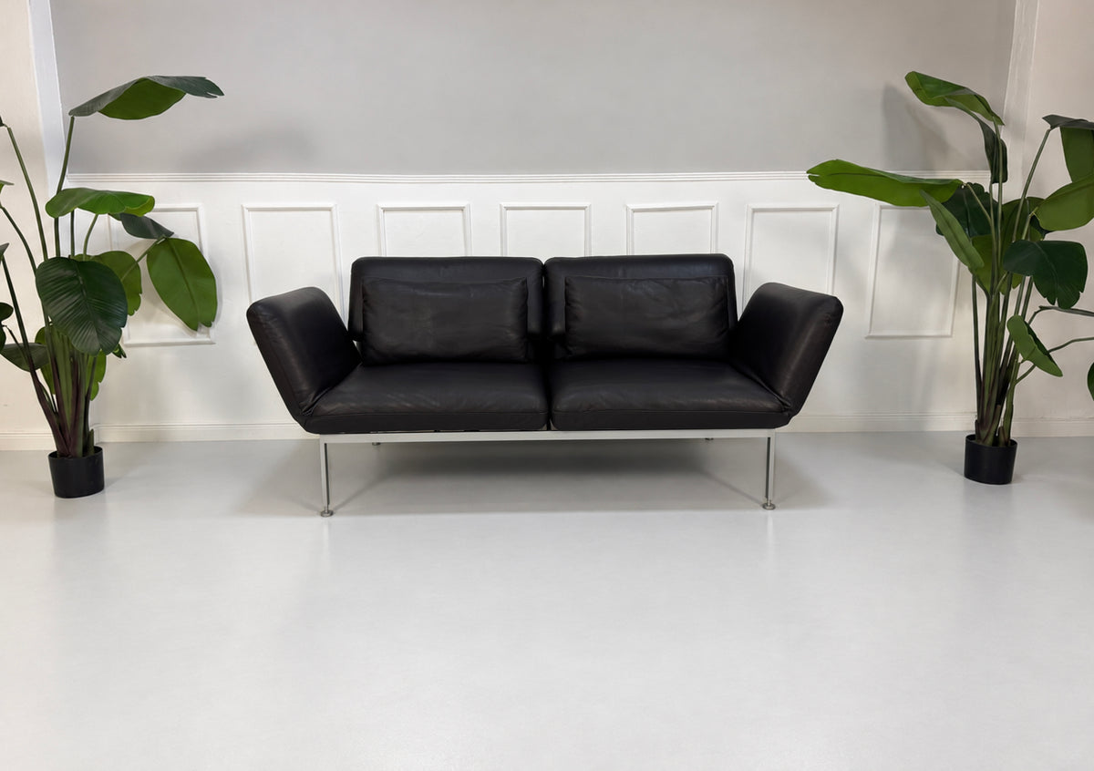 Gebrauchtes schwarzes Brühl Roro Medium Designer Leder Sofa vor einer Wand, stilvoll und modern eingerichtet.