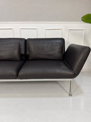 Gebrauchtes schwarzes Brühl Roro Medium Designer Leder Sofa vor einer Wand, stilvoll und modern eingerichtet.