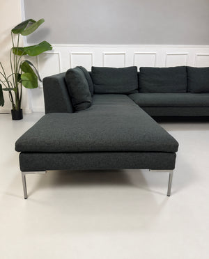 Gebrauchtes graues B&B Italia Charles Designer Stoff Ecksofa vor einer Wand, stilvoll und modern eingerichtet.