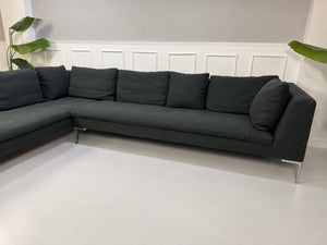 Gebrauchtes graues B&B Italia Charles Designer Stoff Ecksofa vor einer Wand, stilvoll und modern eingerichtet.