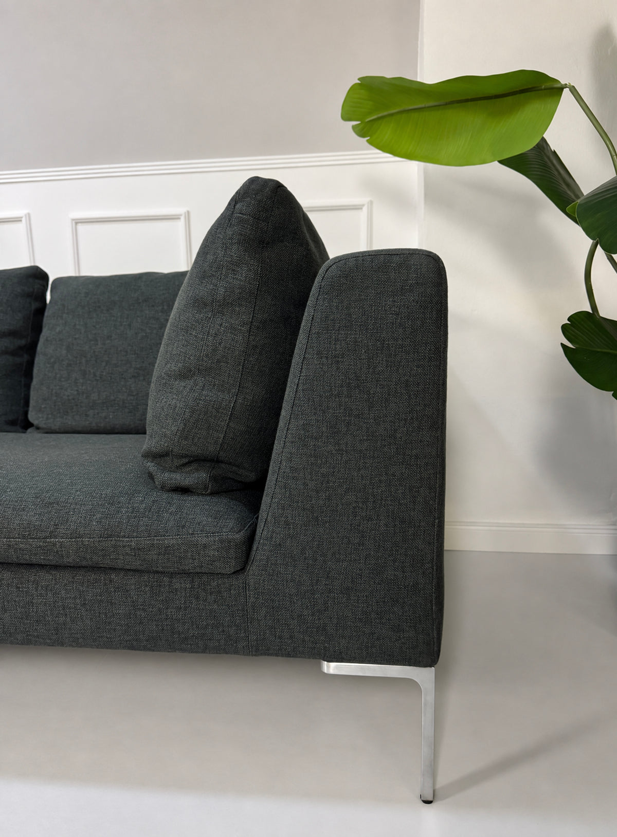 Gebrauchtes graues B&B Italia Charles Designer Stoff Ecksofa vor einer Wand, stilvoll und modern eingerichtet.