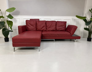 Gebrauchtes rotes Brühl Fourtwo Designer Leder Ecksofa vor einer Wand, stilvoll und modern eingerichtet.