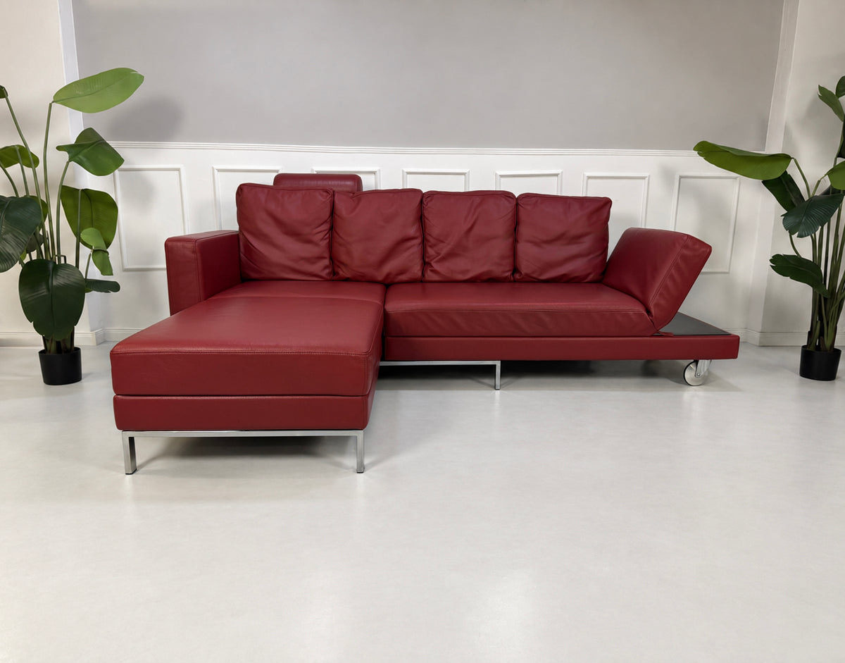Gebrauchtes rotes Brühl Fourtwo Designer Leder Ecksofa vor einer Wand, stilvoll und modern eingerichtet.