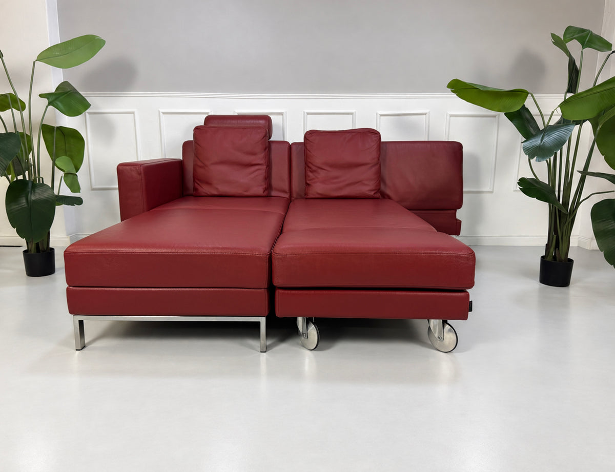 Gebrauchtes rotes Brühl Fourtwo Designer Leder Ecksofa vor einer Wand, stilvoll und modern eingerichtet.