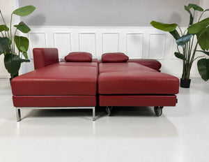 Gebrauchtes rotes Brühl Fourtwo Designer Leder Ecksofa vor einer Wand, stilvoll und modern eingerichtet.