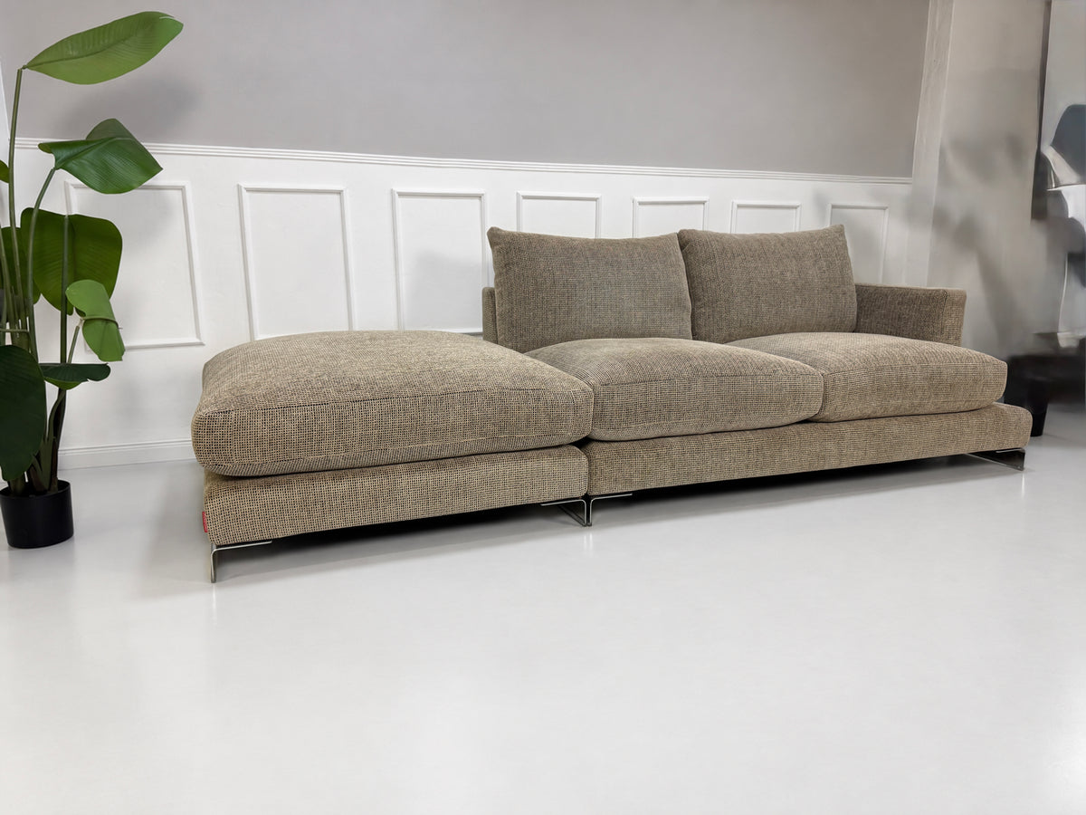 Gebrauchtes beiges Flexform Long Island 05 Designer Stoff Sofa mit Hocker vor einer Wand, stilvoll und modern eingerichtet.